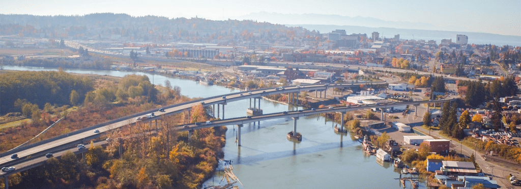 Aerial view of Everett, WA with bridges over a river, highways, and autumnal scenery.