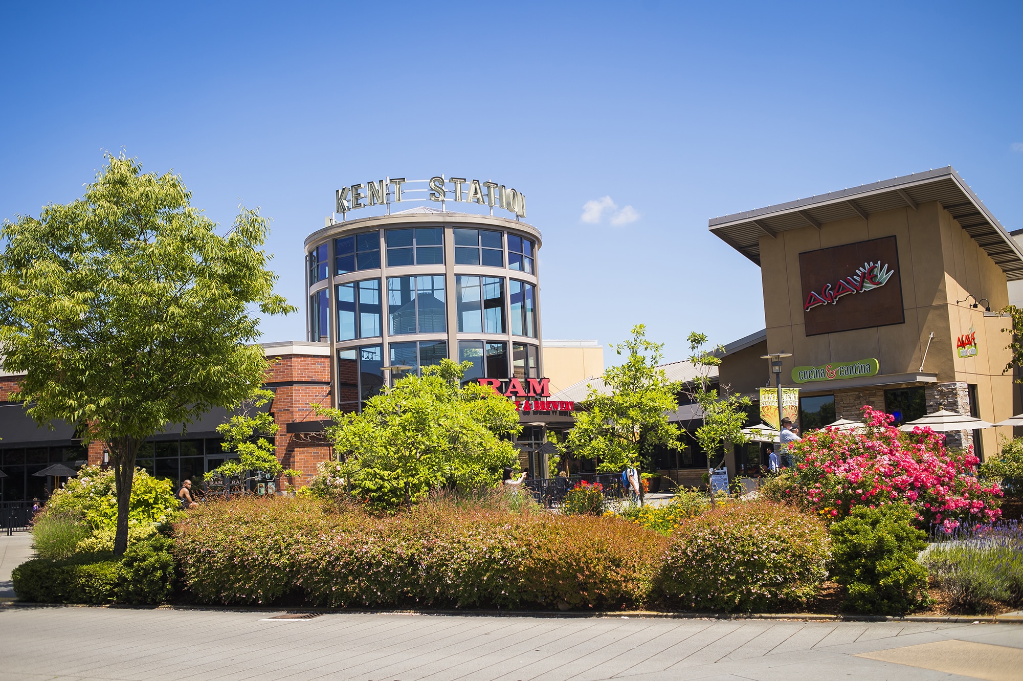 Kent Station shopping center with restaurants, trees, flowers, and a clear blue sky.