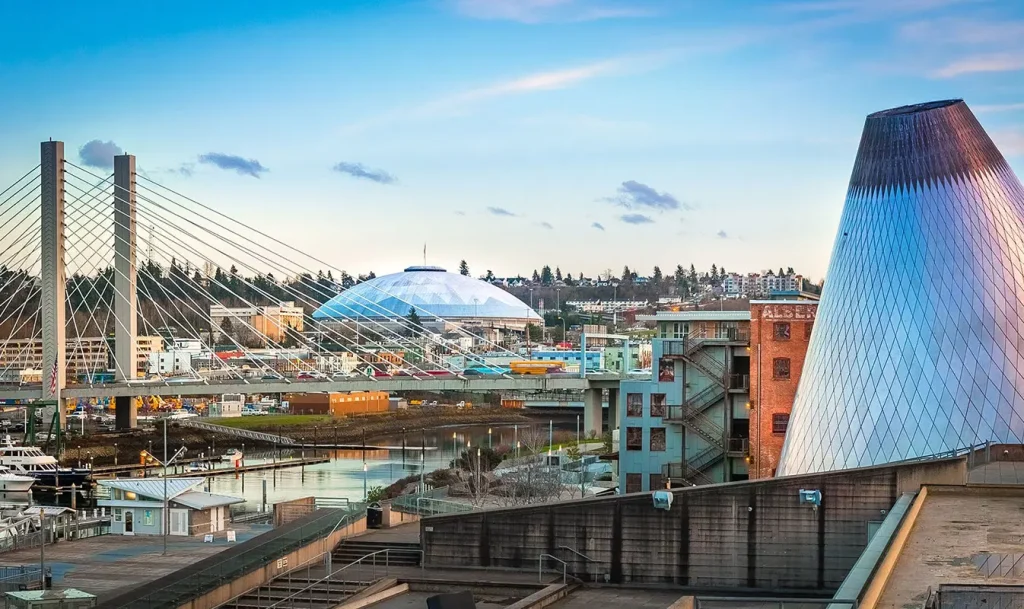 Cityscape with a suspension bridge and a shiny, conical building.
