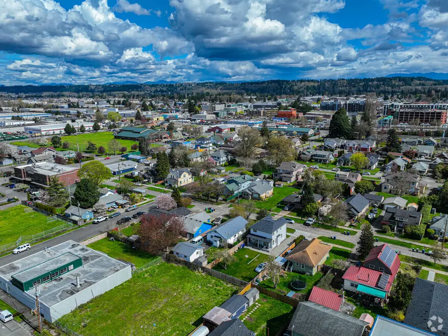 Auburn WA town with homes, green spaces, and hills under a cloudy sky.