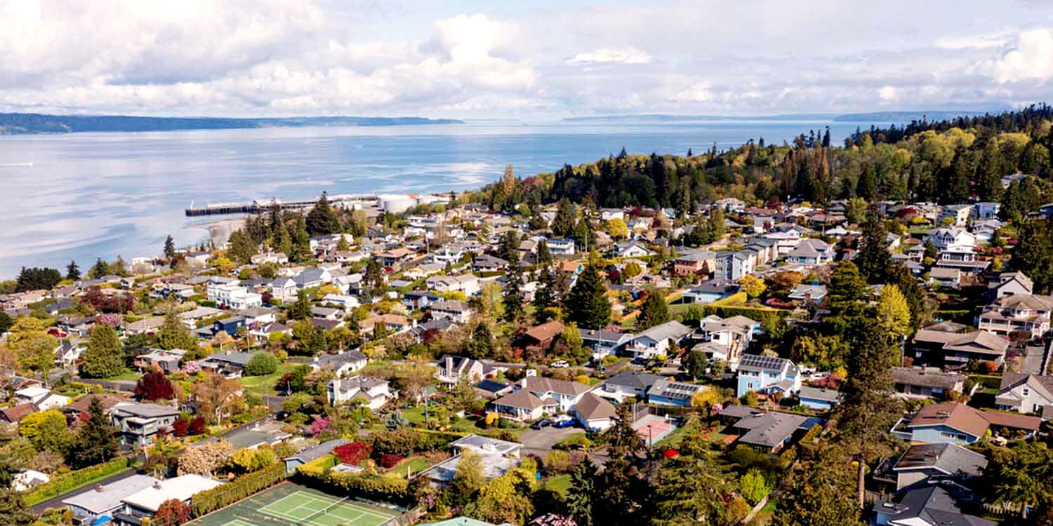 Sumner WA by a river with buildings and hills under a cloudy sky.