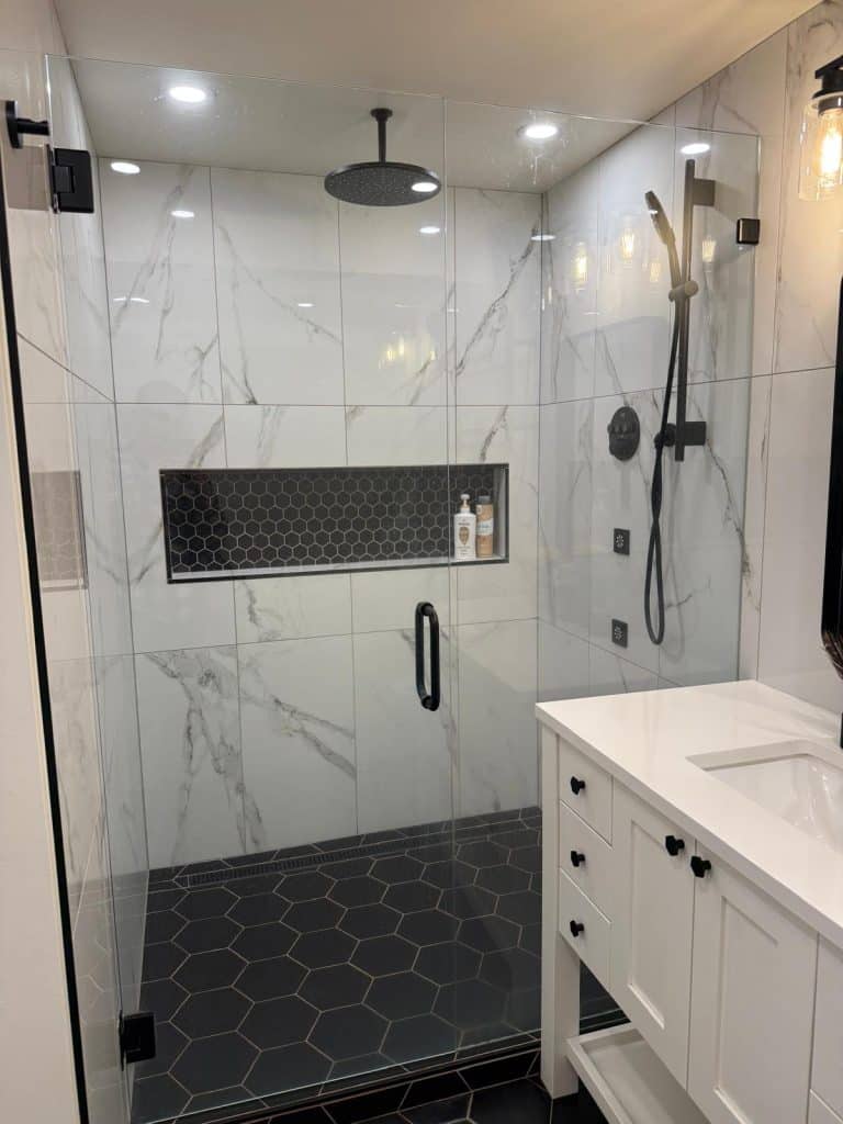 Modern walk-in shower remodel with marble tile and black fixtures by YSG Construct