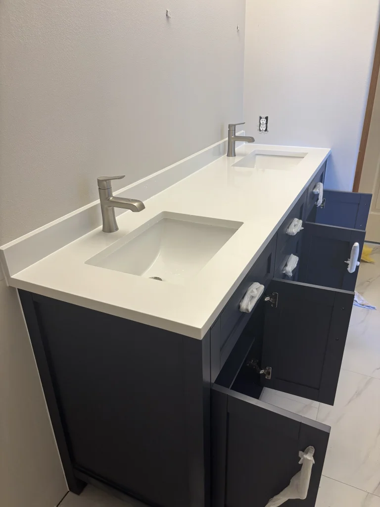 Installed bathroom double vanity with dark blue cabinets and white countertop, a key step in Water Damage Restoration in Seattle WA.