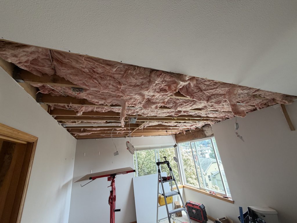 Ceiling opened exposing wet insulation after water damage in Seattle home
