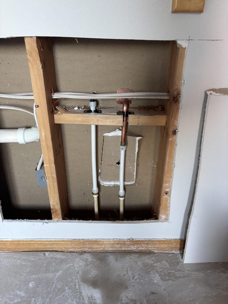 Plumbing manifold with new PEX supply piping installed in opened wall