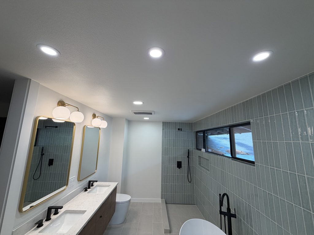 Remodeled bathroom with recessed ceiling lights, vertical tile shower and freestanding tub