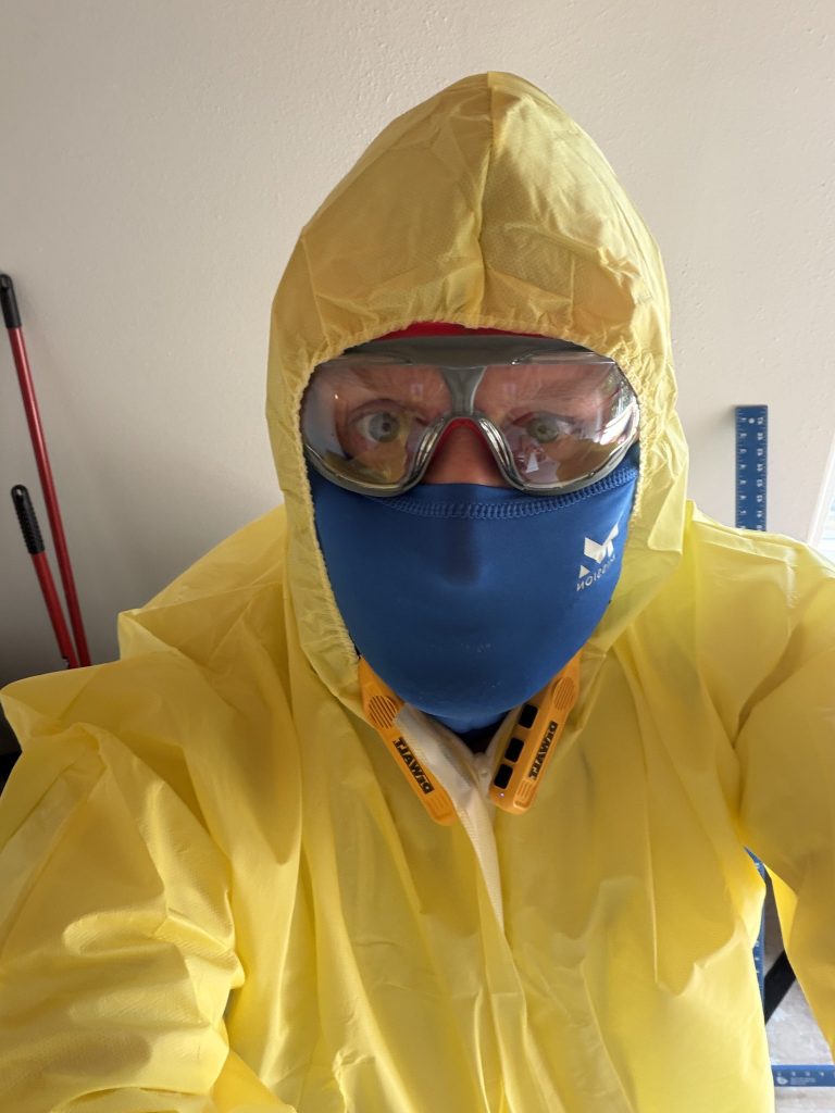 Restoration worker in protective suit and respirator