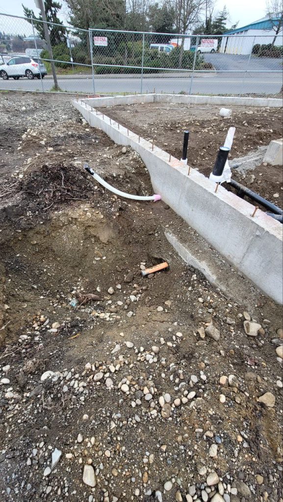 Utility pipes penetrating through concrete strip footing with roughed-in stacks in Tacoma WA by YSG Construct