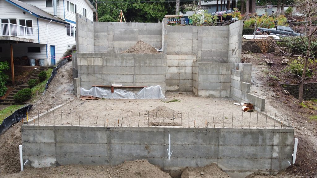 Stepped concrete foundation walls with rebar on a sloped site — YSG Construct foundation work, Ames Lake WA