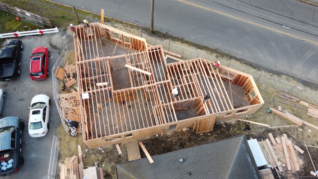 Aerial view of new house framing in progress with workers on the wooden structure — YSG Construct