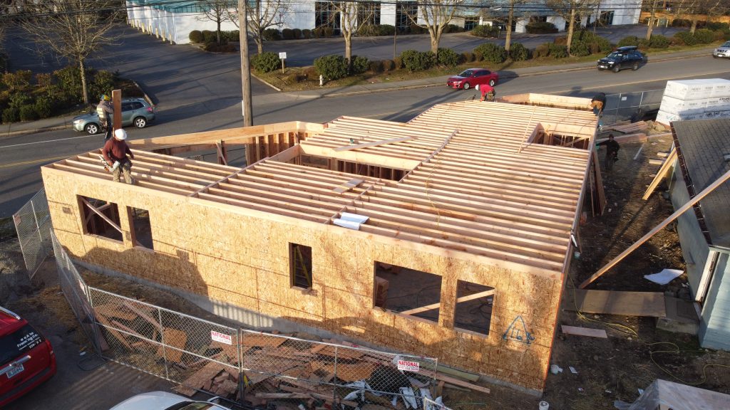 Wood wall framing with window openings and a worker using a nail gun — YSG Construct