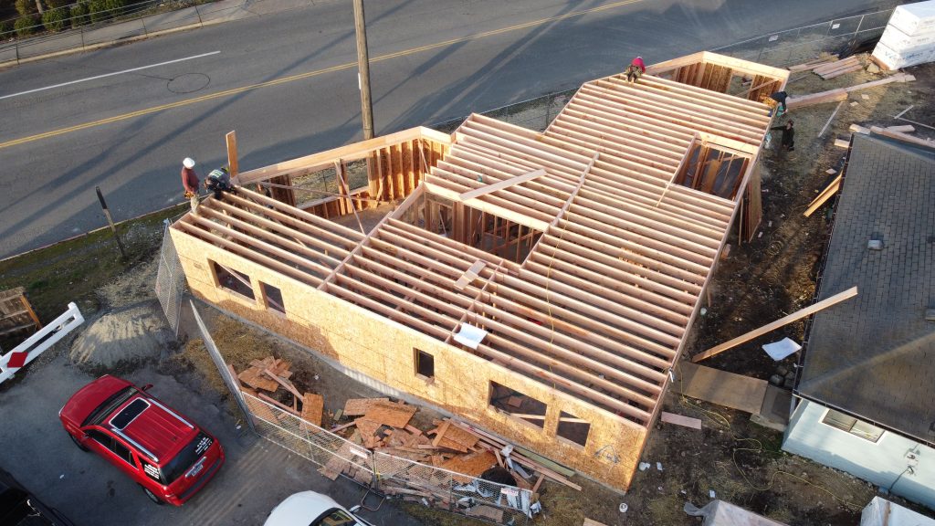 Aerial view of house framing with workers on the top plate, new construction — YSG Construct