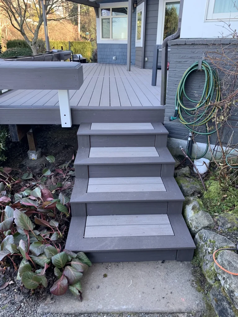 Gray composite deck with steps down to the garden, built by YSG Construct