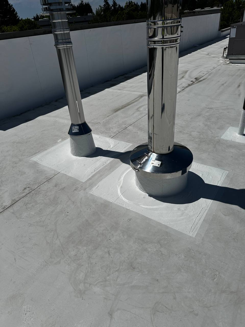 Sealed stainless steel HVAC vent pipes on flat commercial roof in Lacey WA by YSG Construct