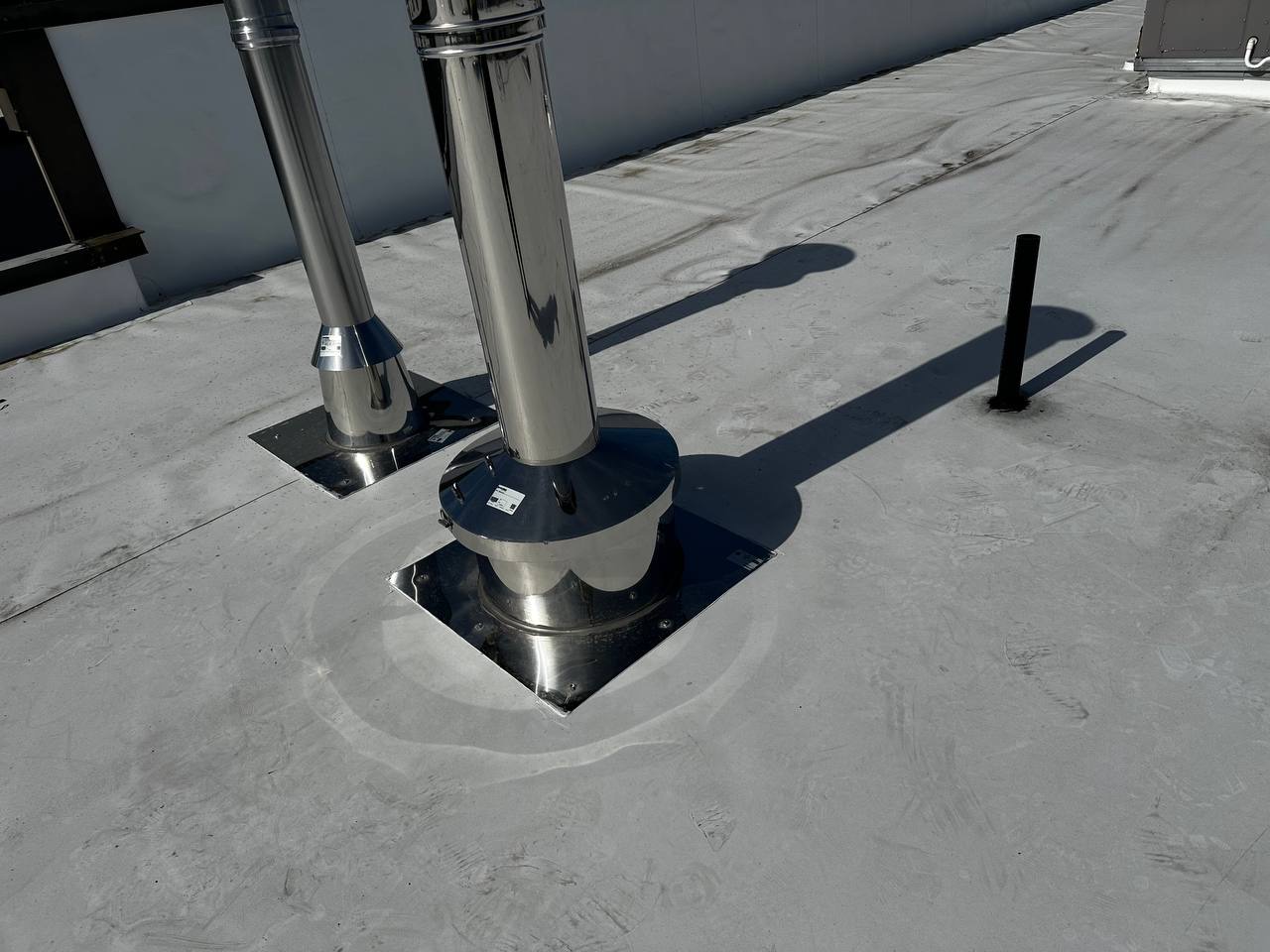 Stainless steel vent pipes with square flashing plates on commercial flat roof in Lacey WA