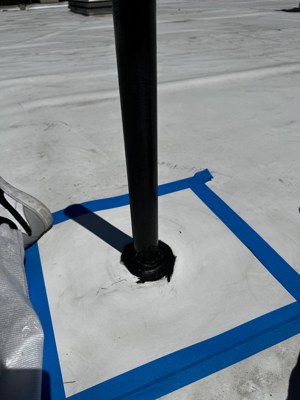 Applying sealant around a black roof pipe penetration in Lacey WA