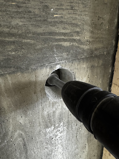 Flexible conduit fitting sealed through cored hole in concrete wall