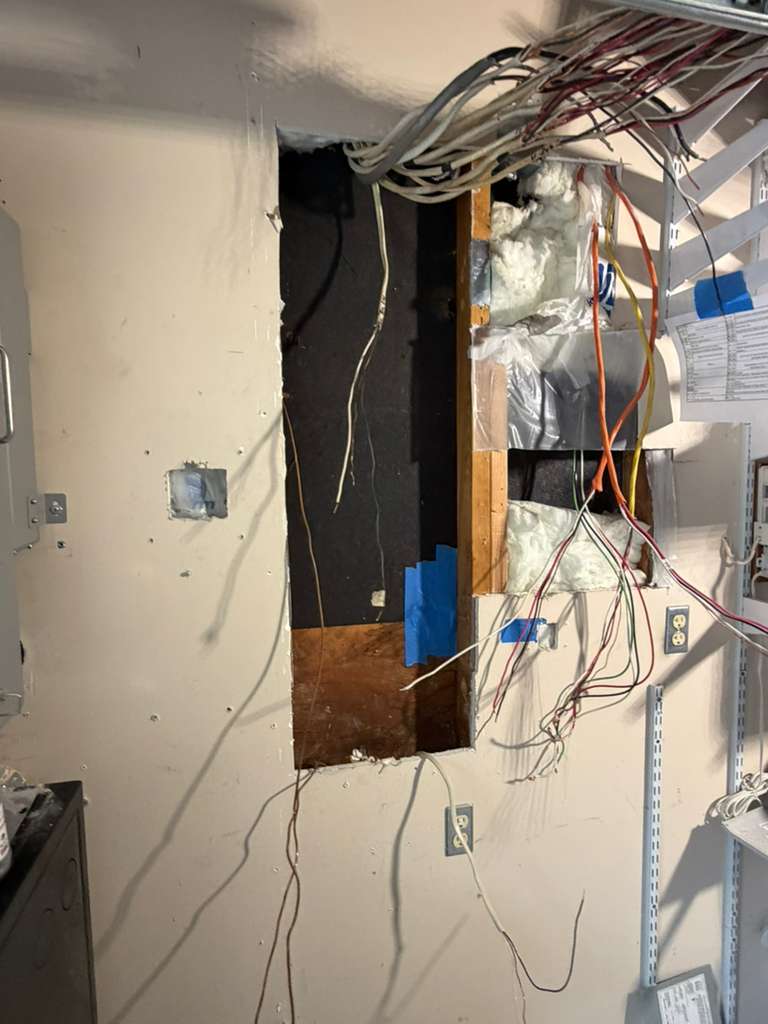 Wall opened for wiring runs during a battery backup project in Redmond, WA