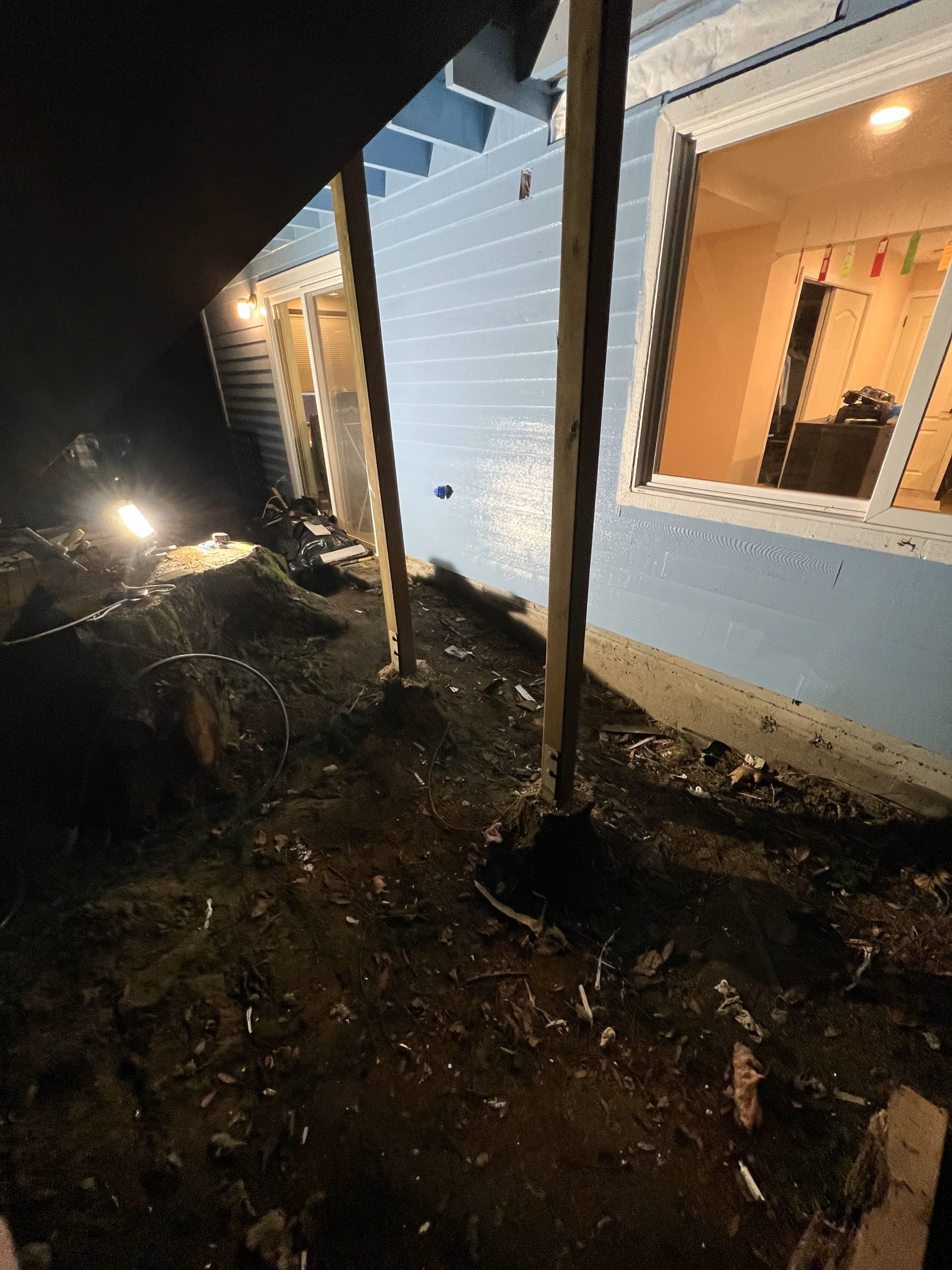 Rebuilt exterior wall with new siding at night in Redmond WA by YSG Construct